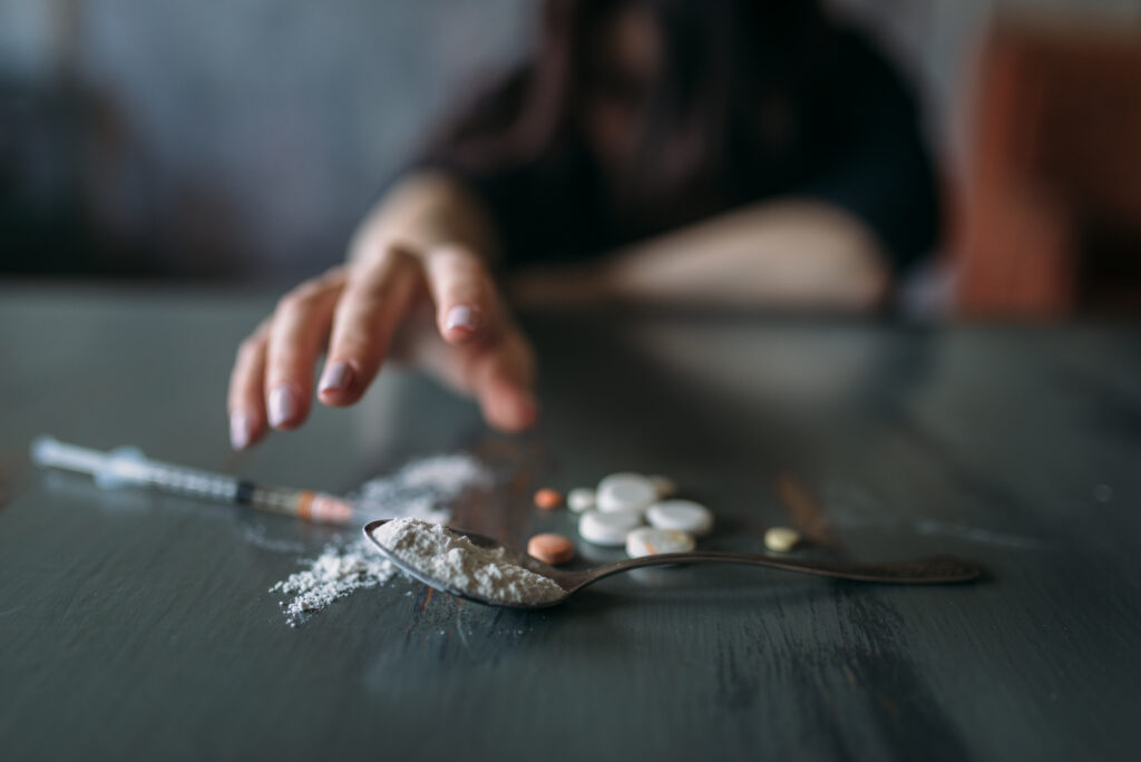 Fentanyl Addiction Signs: Recognizing the Warning Signs and Seeking Help. Female junkie hand hand reaching for the dose on the table. Drug addiction