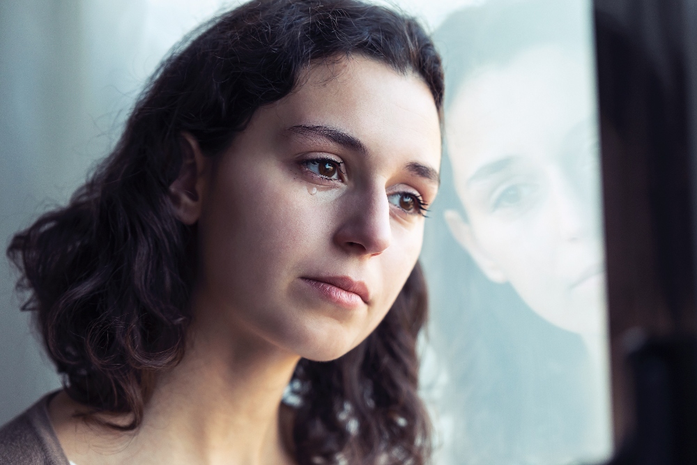 woman crying looking out window - ocd treatment los angeles